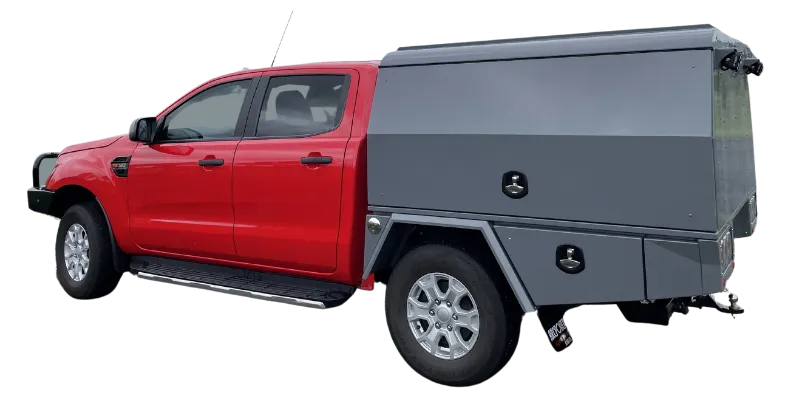 A red pickup truck with a large dark gray hardtop canopy bed, shown from a three-quarter rear angle on a plain white background.