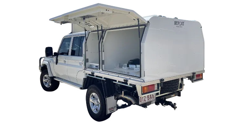 A white pickup truck with a large white rooftop camper shell and side storage compartments, shown from a rear three-quarter angle on a plain white background.